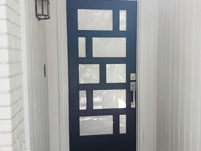 A black contemporary entry door with staggered rectangular glass lites