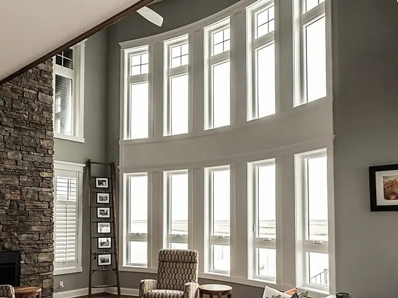 A double-height curved wall of white-framed windows in a living room