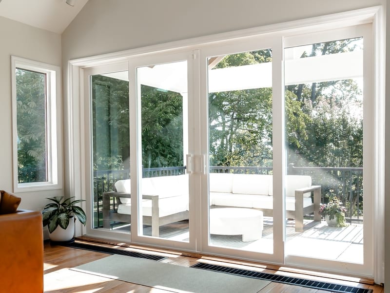 A white sliding patio door standing open onto a shaded terrace